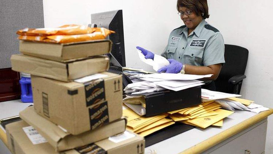 Corrections officer manually screening mail